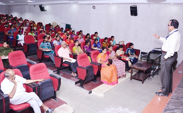 Commerce Department seminar at PKR Arts College for Women, with a speaker addressing students seated in an auditorium