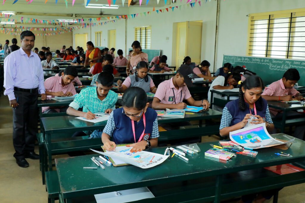 Students participate in an art competition inside a decorated classroom, concentrating on drawing and coloring at long desks while teachers supervise the session.